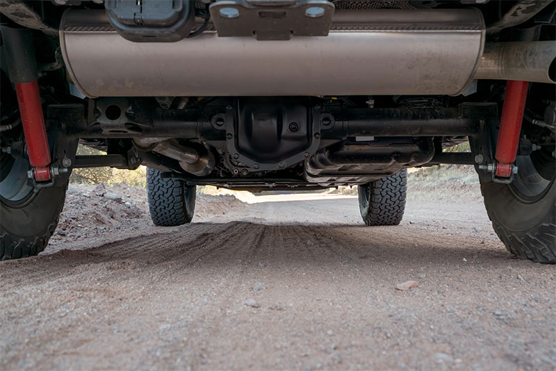 View of the drivetrain underneath a truck, including differential and axle