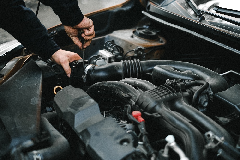 A mechanic uses a screwdriver to reassemble a used engine